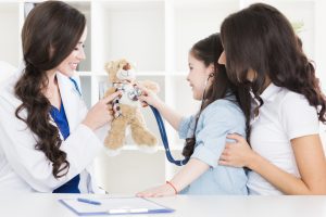 Pediatrists examine heart beat of teddy bear of small girl.