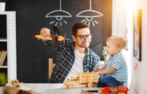 Happy family father and son toddler gather craft a car out of wood and play.